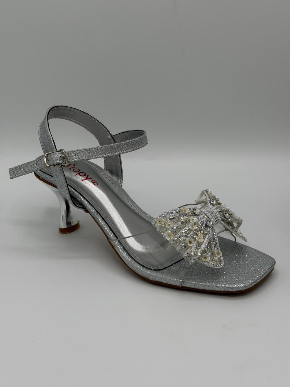 Silver sandal with decorative bow on a gray background