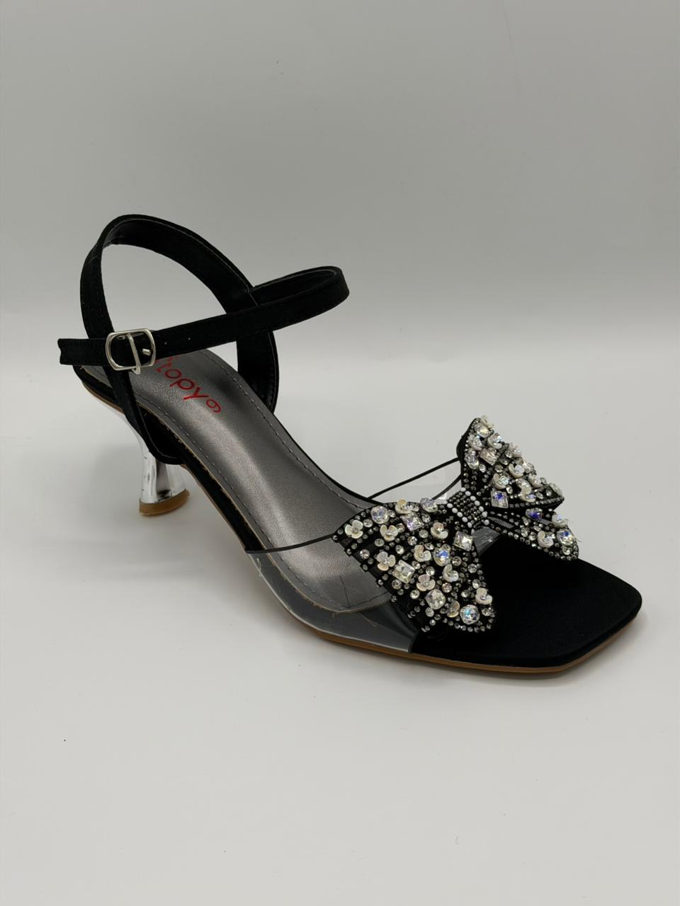 Black high-heeled sandal with decorative bow on a gray background