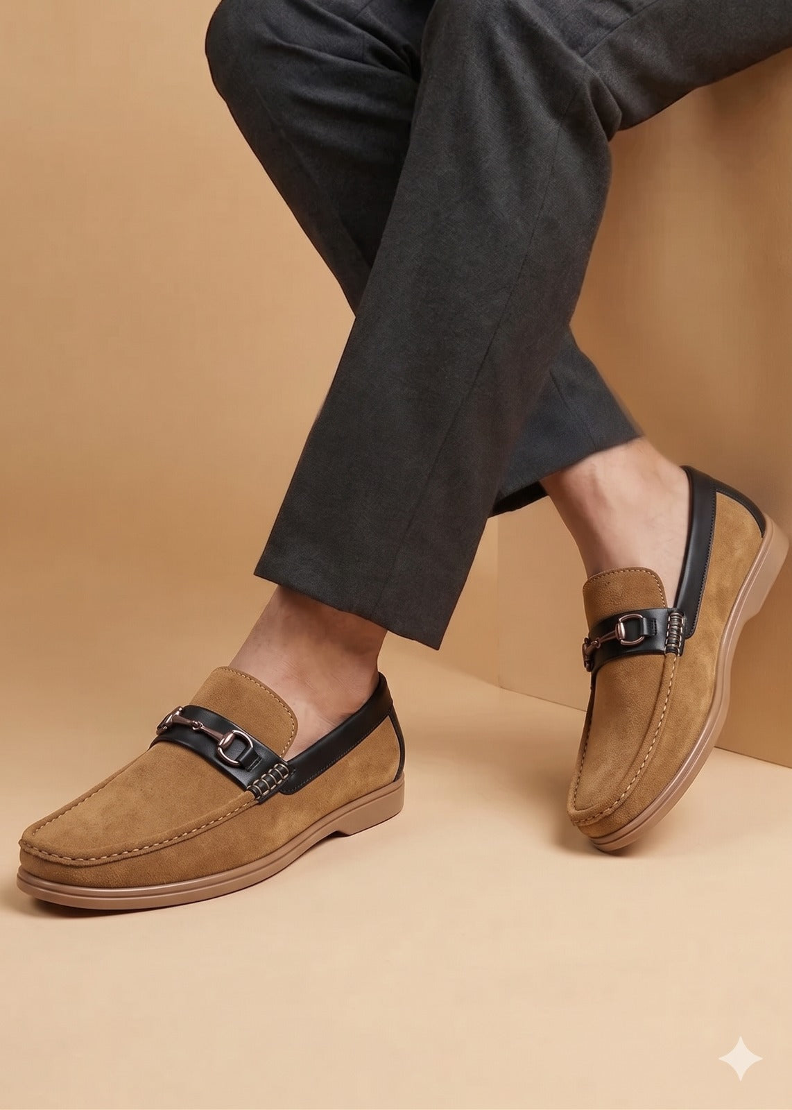 Brown loafers worn with dark pants on a beige background