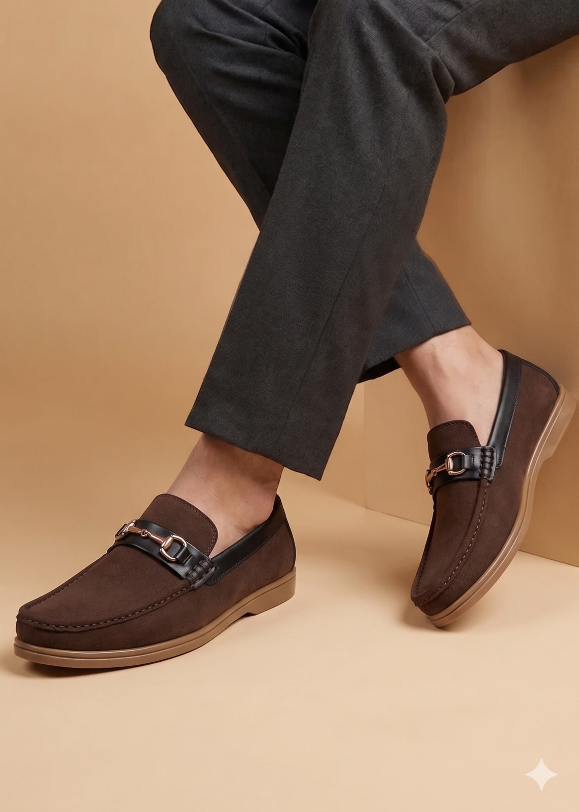 Brown loafers worn with dark pants on a beige background