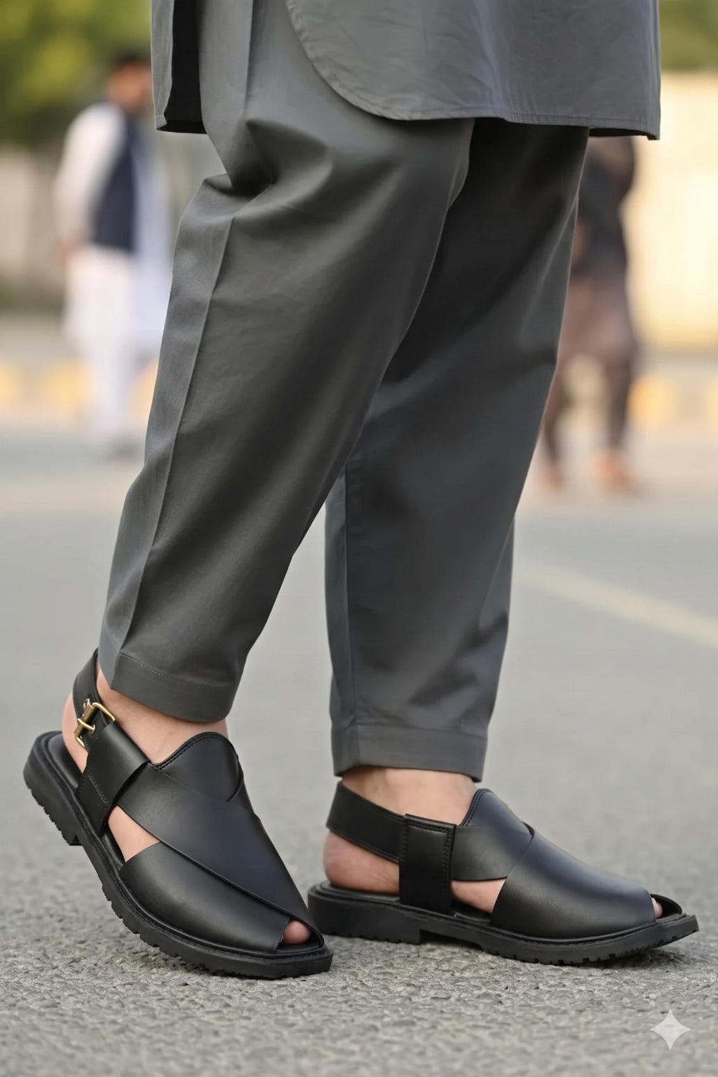 Person wearing black sandals and gray pants on a blurred street background