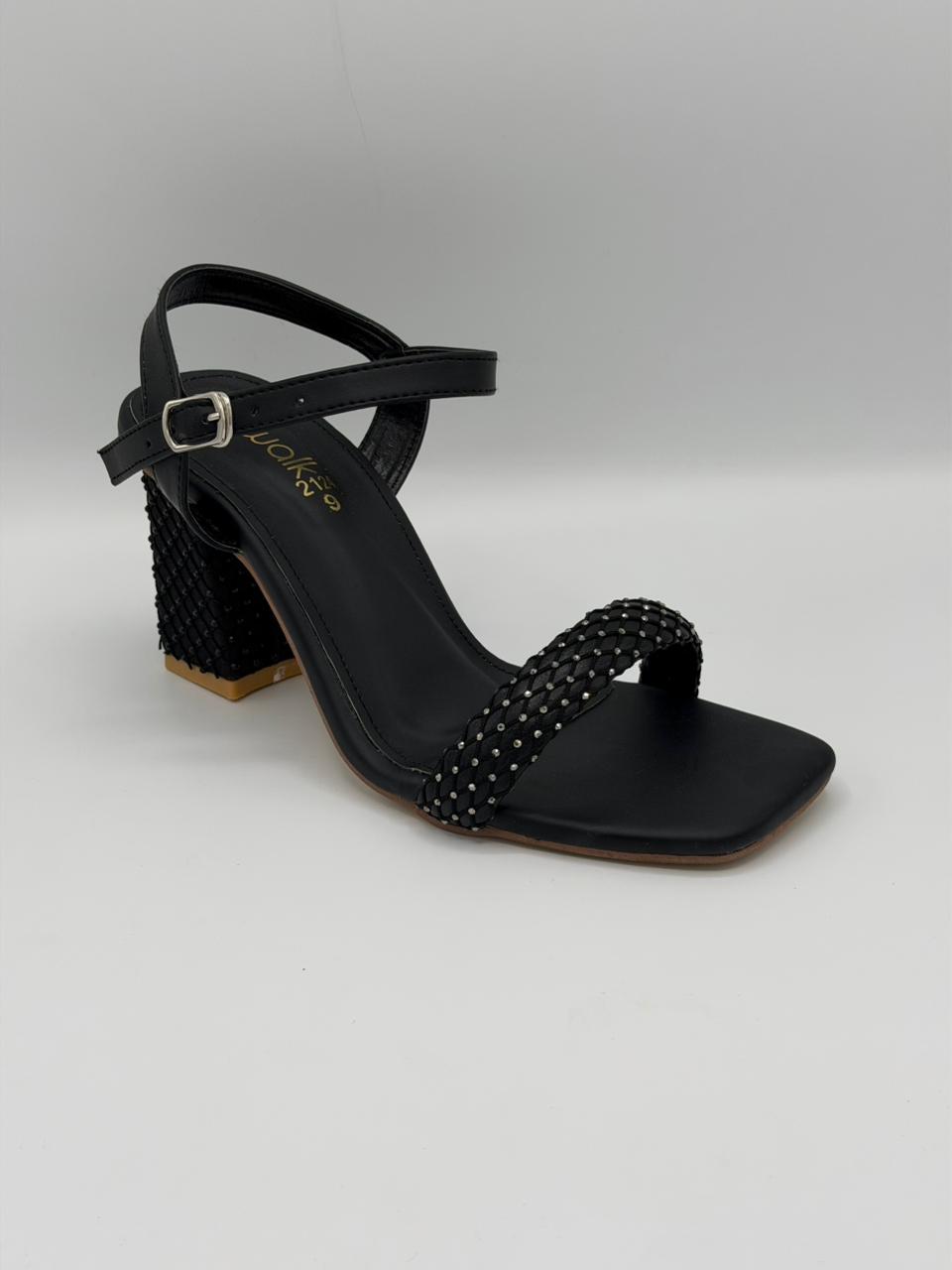 Black sandal with studded details on a light gray background
