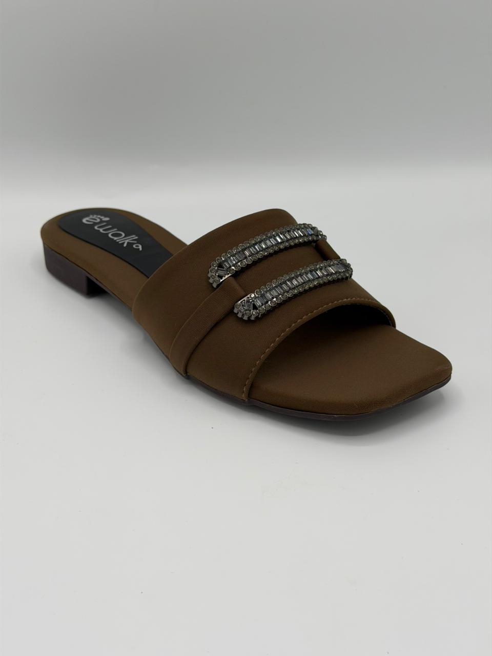 Brown sandal with embellishments on a gray background