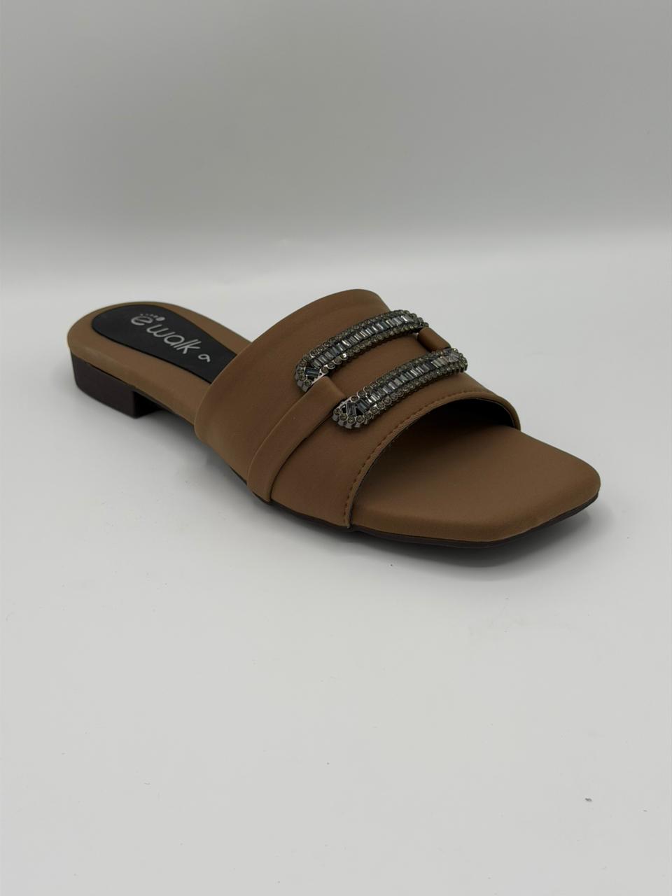 Brown sandal with embellishments on a gray background