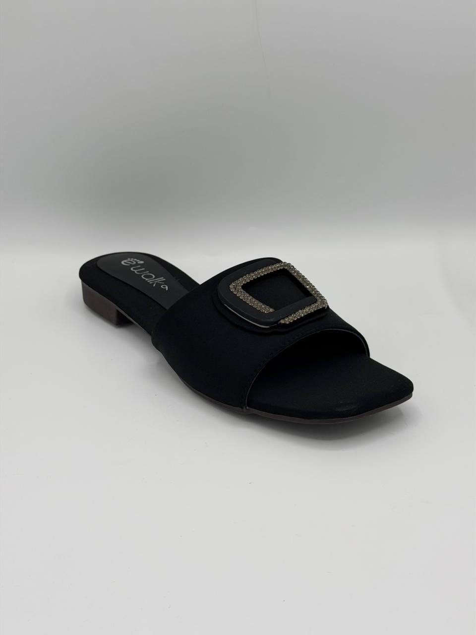 Black sandal with a square buckle on a light gray background