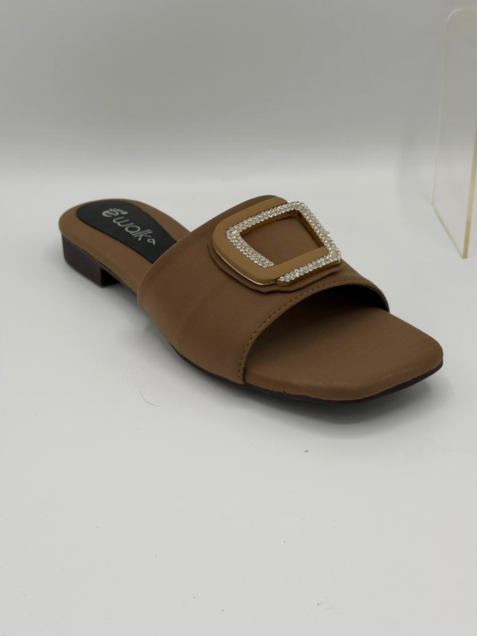 Brown sandal with a decorative buckle on a white background