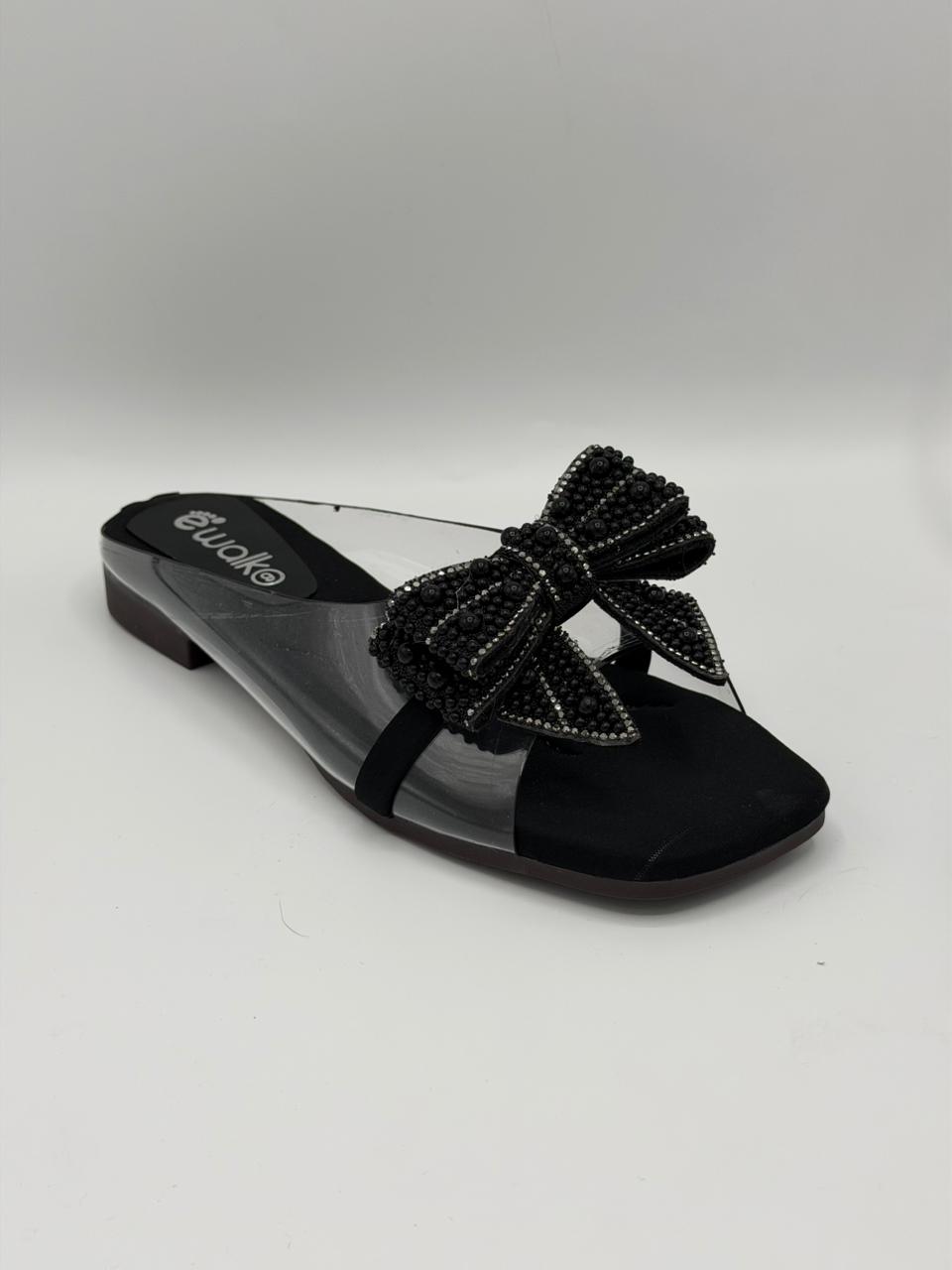 Black sandal with a decorative bow on a light gray background