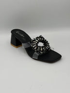 Black sandal with decorative element on a gray background