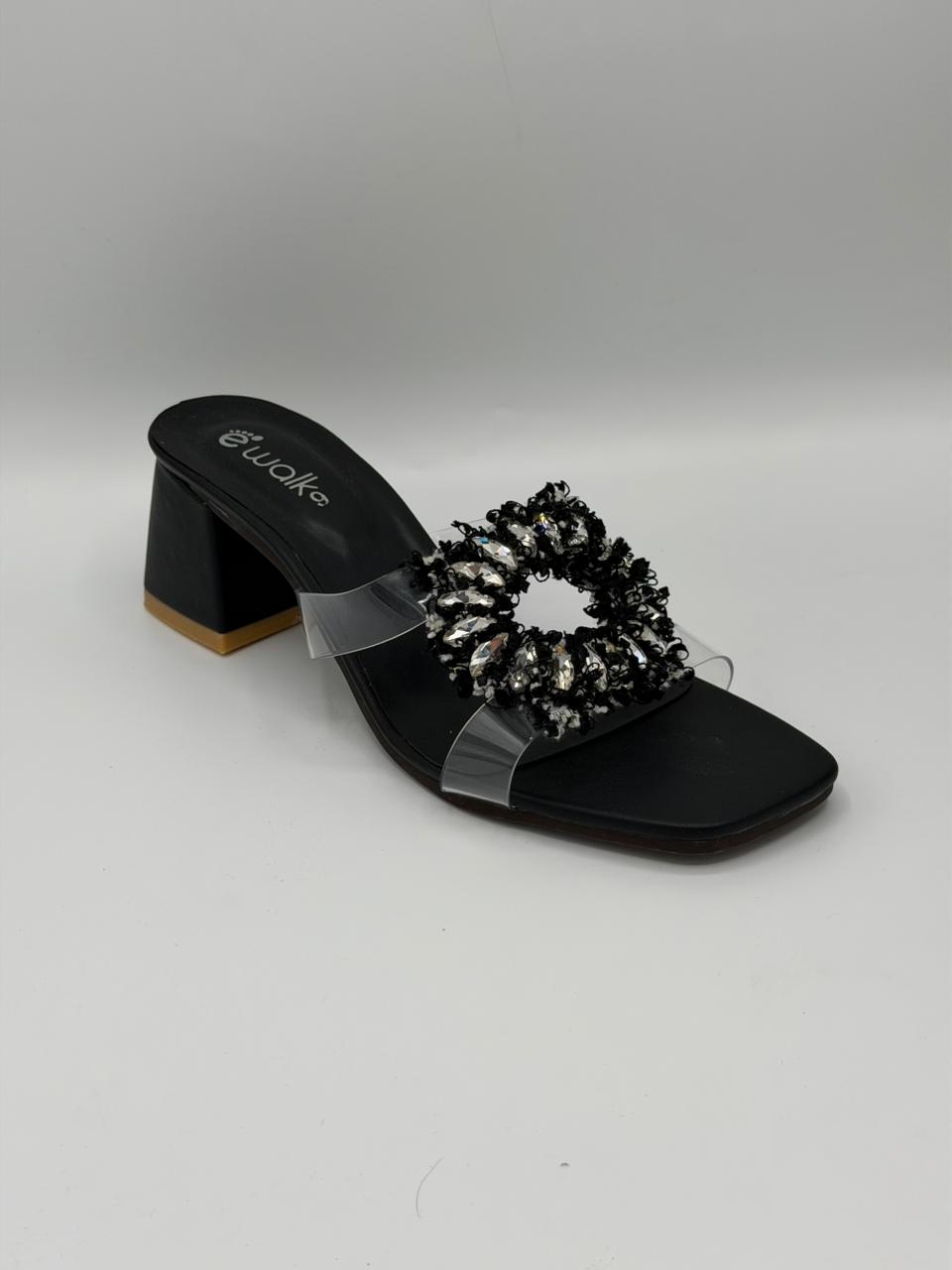 Black sandal with decorative element on a gray background