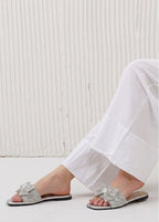 Silver sandals worn with white pants against a light background