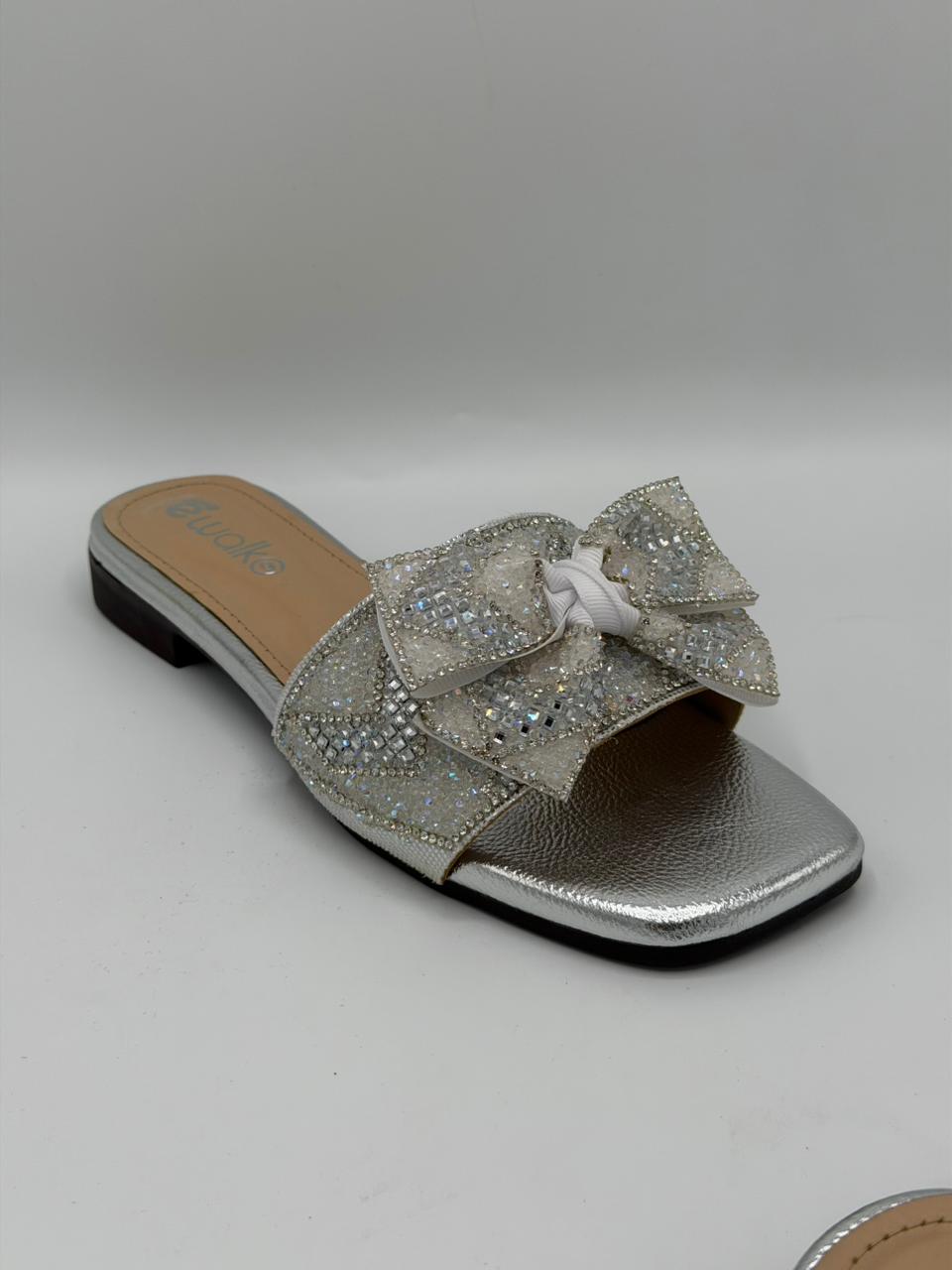 Silver glitter sandal with a bow on a gray background