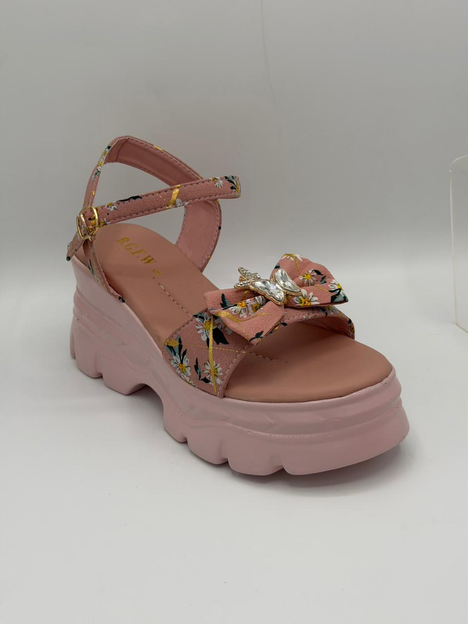 Pink sandal with floral straps and embellishments on a white background