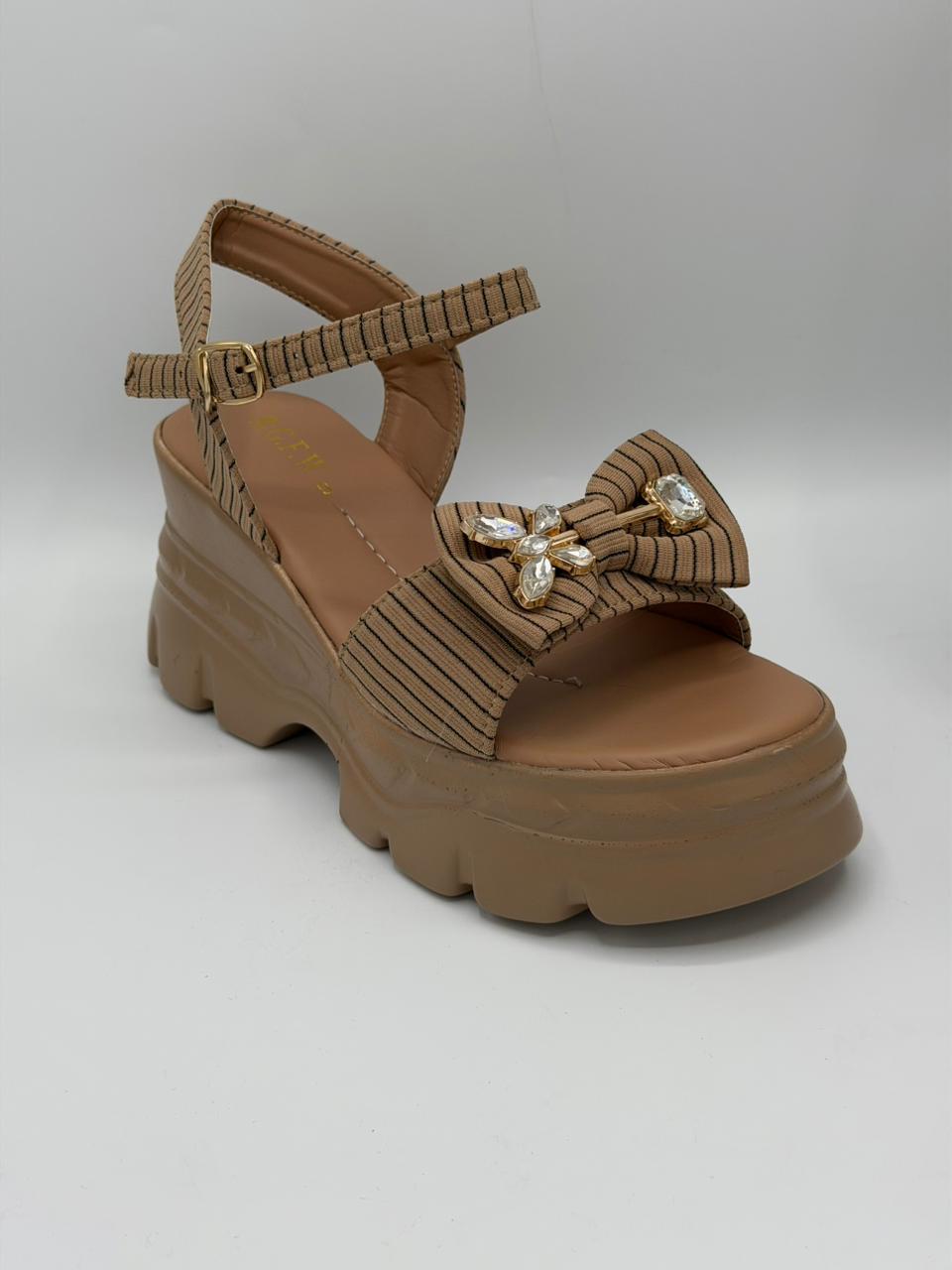 Brown platform sandal with decorative bow on a white background