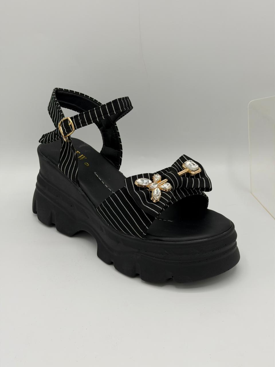 Black sandal with platform sole and decorative elements on a white background
