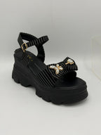 Black sandal with platform sole and decorative elements on a white background