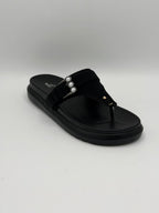 Black sandal with pearl embellishments on a gray background