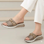 Brown sandals with gold accents worn by a person on a light background