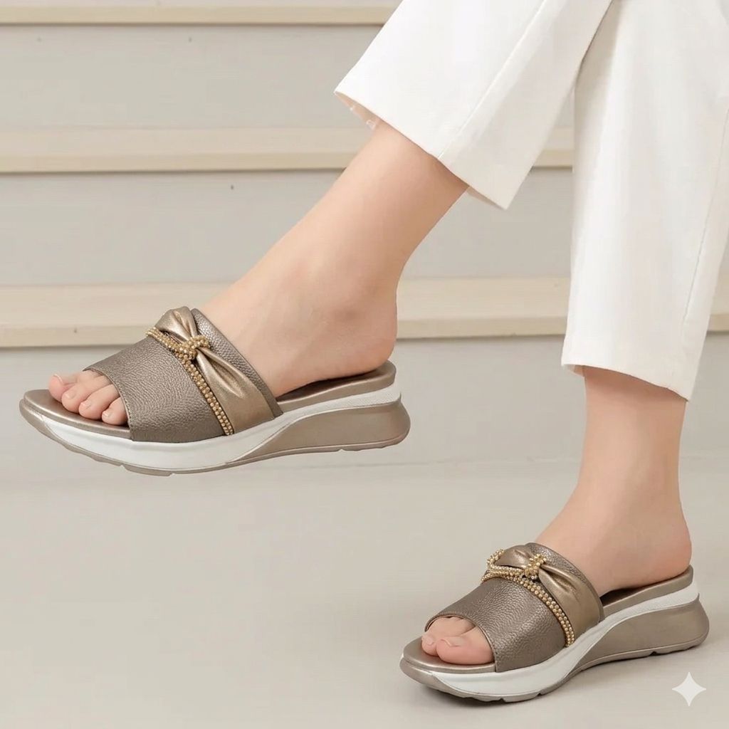Brown sandals with gold accents worn by a person on a light background