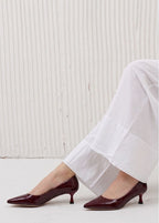 Brown high-heeled shoes worn with white pants against a light background