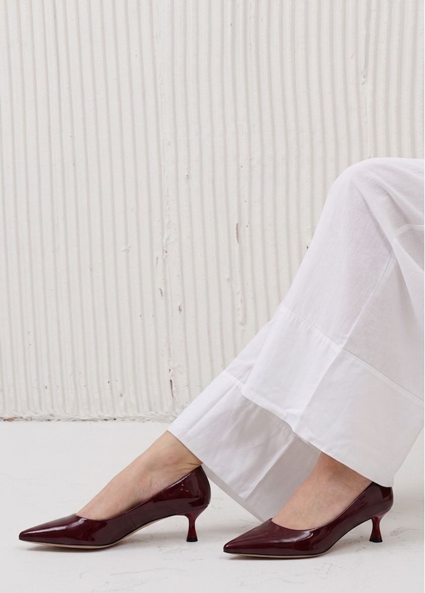 Brown high-heeled shoes worn with white pants against a light background