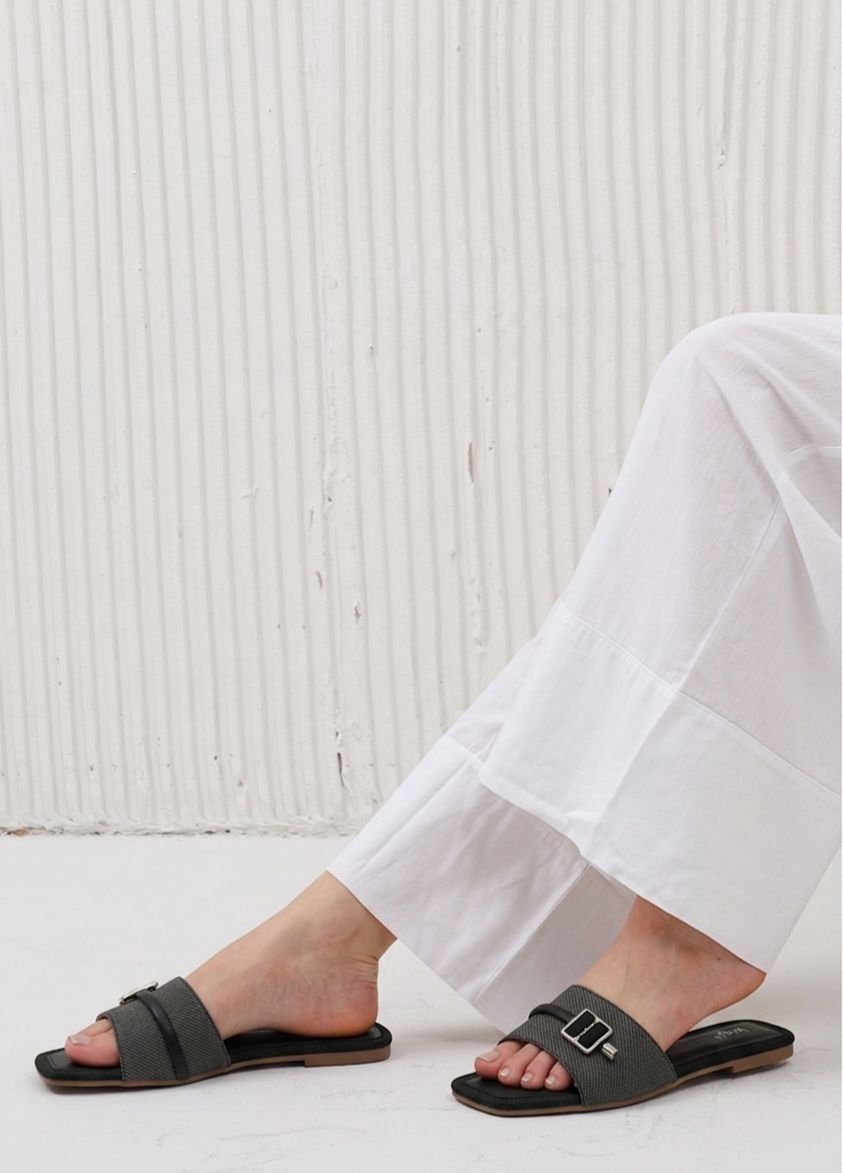 Person wearing black sandals with a white textured background