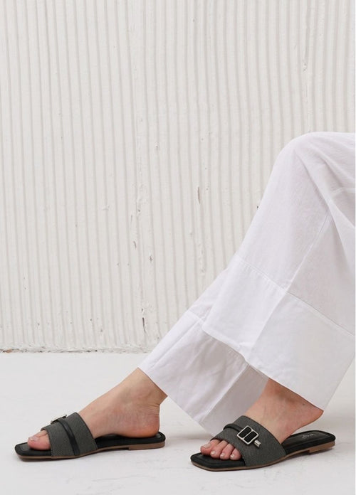 Person wearing black sandals with a white textured background