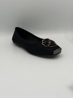 Black flat shoe with decorative element on a gray background