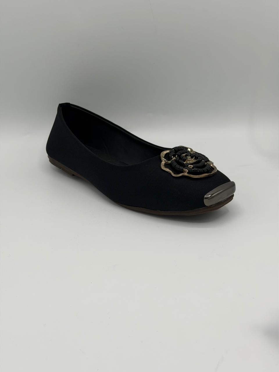 Black flat shoe with decorative element on a gray background