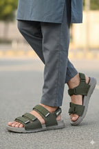 Person wearing green sandals with gray soles on a blurred outdoor background