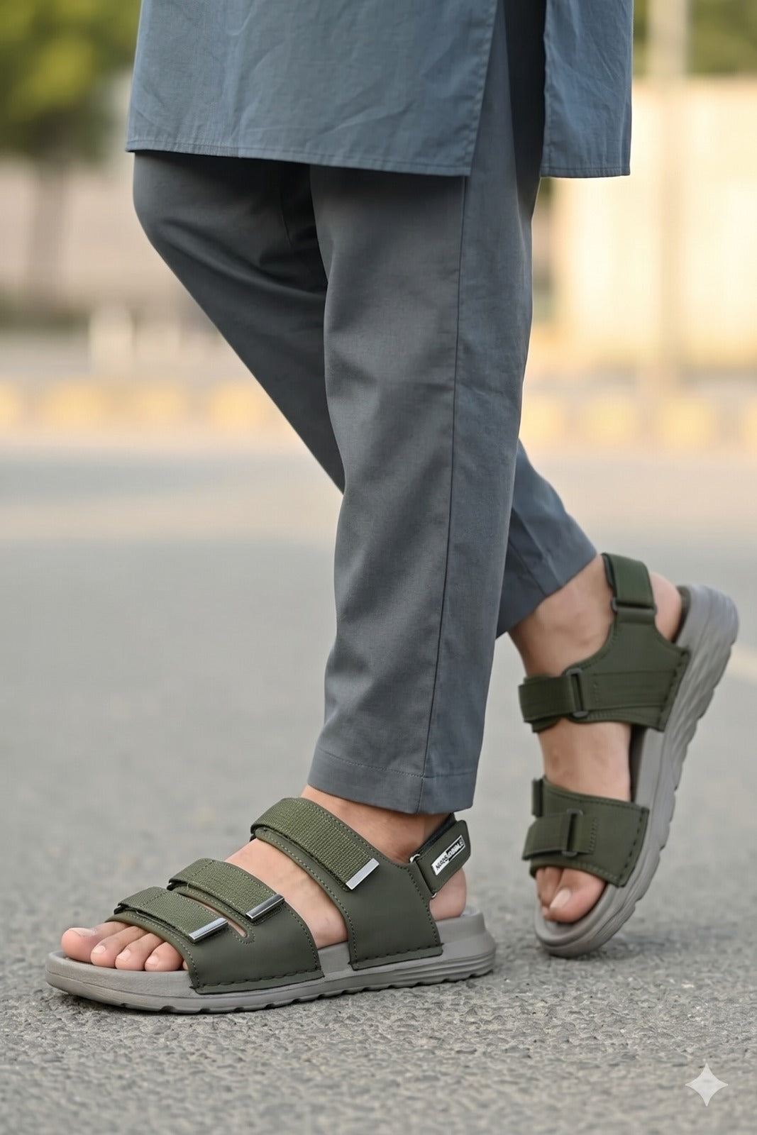Person wearing green sandals with gray soles on a blurred outdoor background