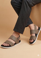 Brown sandals worn with black pants on a beige background