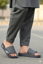 Person wearing gray sandals and pants on a blurred street background