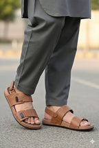 Brown sandals worn with gray pants on a blurred street background