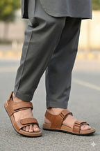 Person wearing brown sandals and gray pants on a blurred street background