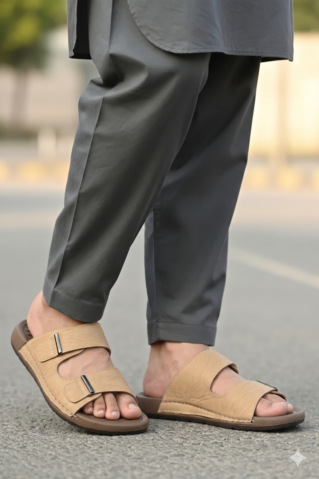 Person wearing beige sandals and gray pants on a blurred street background