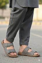 Person wearing gray sandals and pants on a blurred street background