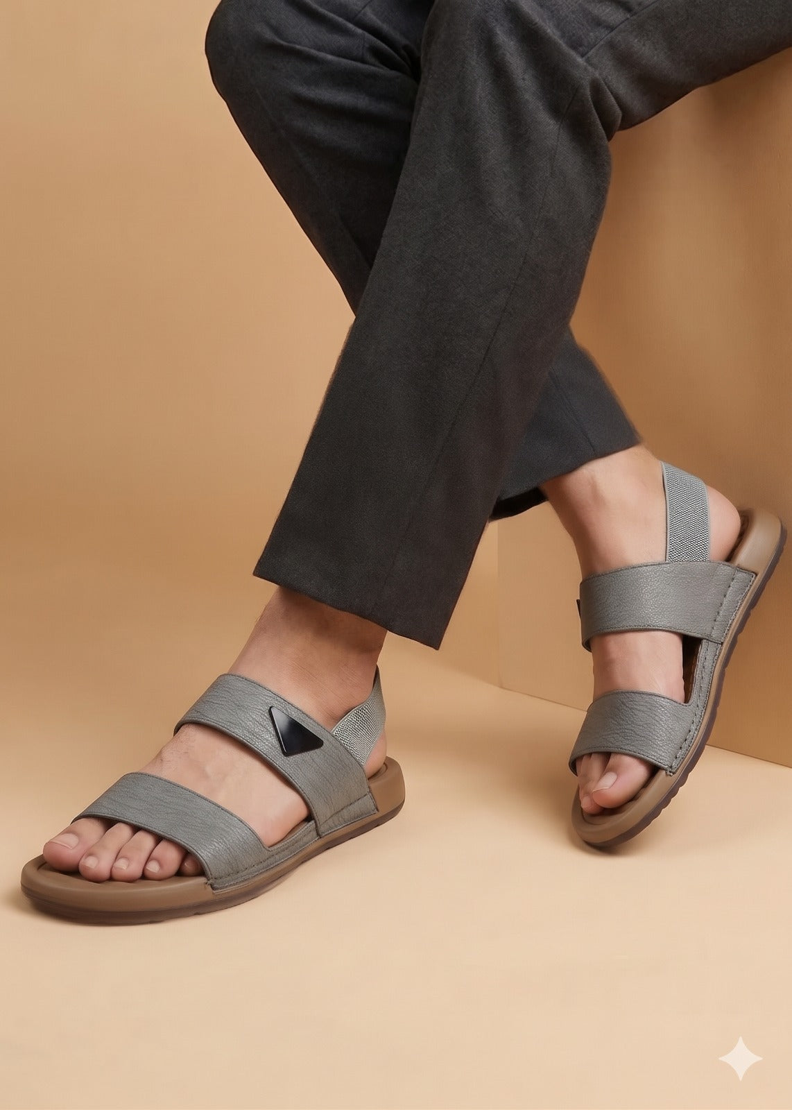 Gray sandals worn with dark pants on a beige background